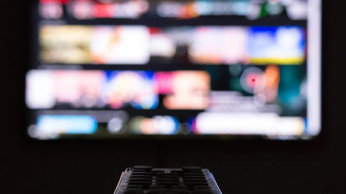 Fernbedienung vor einem Smart-TV mit geöffnetem IPTV-Player-Menü