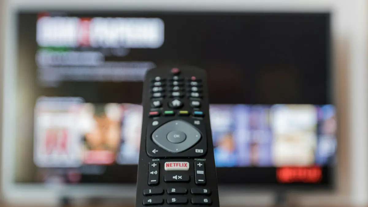Fernbedienung vor Bildschirm mit deutschsprachigem IPTV-Menü und Sprachauswahl